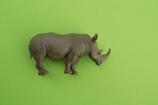 An rhinoceros animal is a children's toy. Plastic figurine for the game. Green background. Farm and the zoo. - Valokuva, kuva