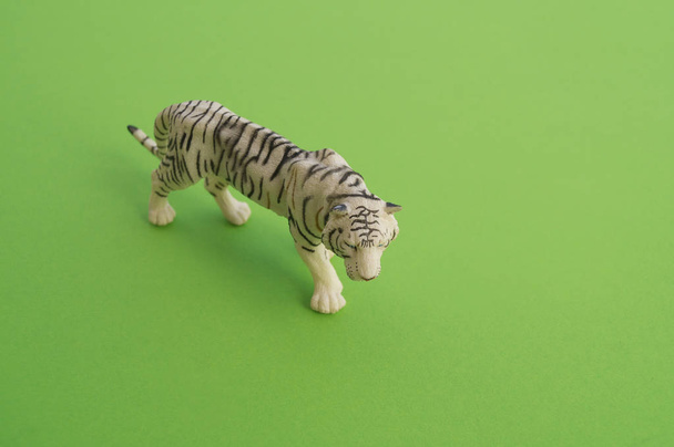An tiger animal is a children's toy. Plastic figurine for the game. Green background. Farm and the zoo. - Zdjęcie, obraz