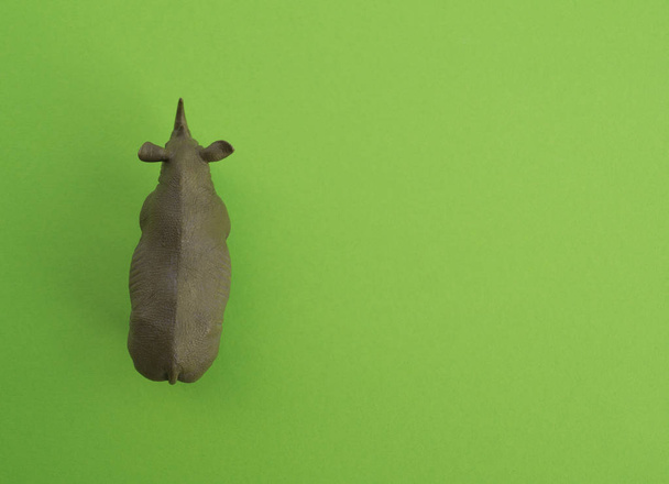 An rhinoceros animal is a children's toy. Plastic figurine for the game. Green background. Farm and the zoo. - Fotó, kép