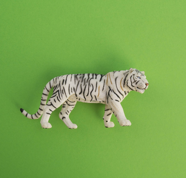 An tiger animal is a children's toy. Plastic figurine for the game. Green background. Farm and the zoo. - Fotografie, Obrázek