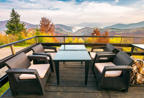 Terrasse mit schönem Blick in die Berge. Herbstzeit mit rotem Laub auf bewaldeten Hügeln. Wolkenumkehrung im fernen Tal. Wunderbares Urlaubskonzept - Foto, Bild
