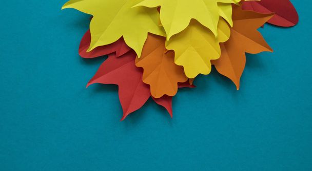 Hojas de papel caen rojo, naranja, amarillo caída de la hoja. Fondo azul. Origami hecho a mano
. - Foto, imagen