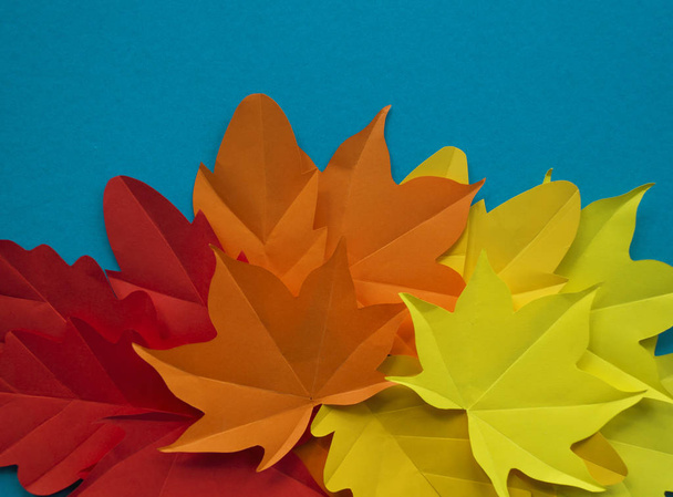 Leaves of paper fall red, orange, yellow leaf fall. Blue background. Handmade origami. - Foto, afbeelding