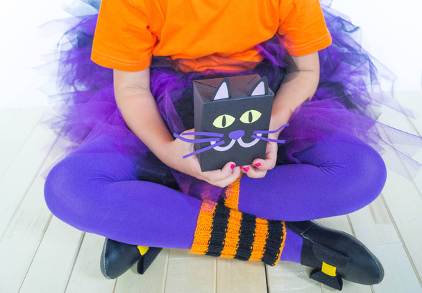 A little girl in a witch costume holds a black cat. Halloween party. Hand made gift wrapping. - Fotoğraf, Görsel
