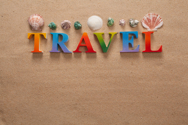 top view of travel written in colorful letters decorate with shellfish on the beach with copy space - Photo, Image