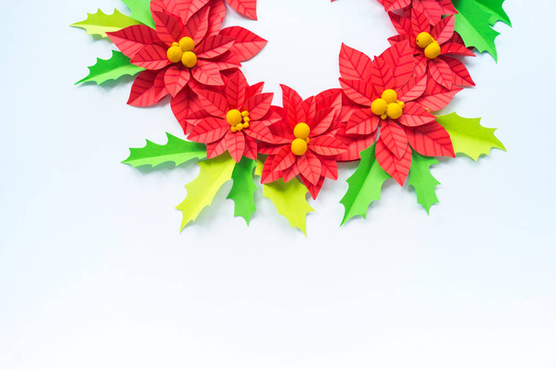 Paper flower poinsettia and leaves of holly. Christmas wreath. White background. Colors are green, red, yellow. - Фото, зображення