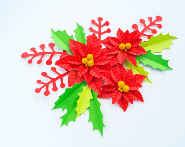 Paper flower poinsettia and leaves of holly. Christmas wreath. White background. Colors are green, red, yellow. - 写真・画像