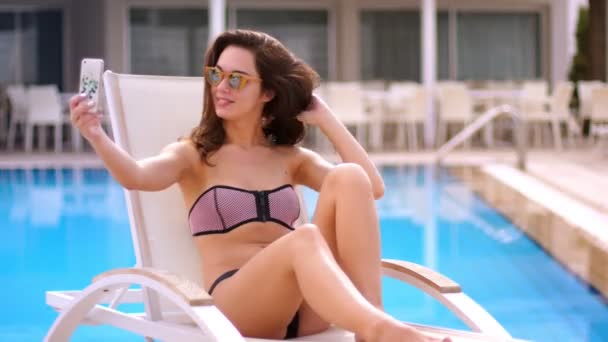 Sexy woman making selfie at swimming pool. Pretty woman take a picture on mobile - Video, Çekim