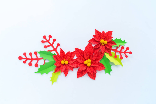 Paper flower poinsettia and leaves of holly. Christmas wreath. White background. Colors are green, red, yellow. - Foto, Bild
