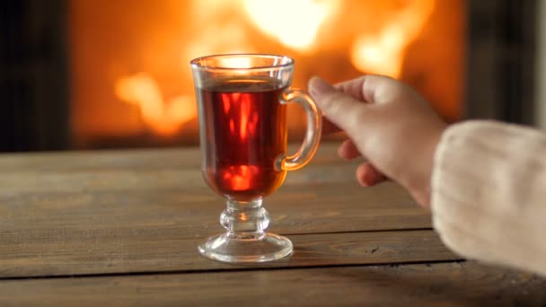 Closeup 4k footage of young woman in sweater drinking hot tea by the burning fireplace - Footage, Video