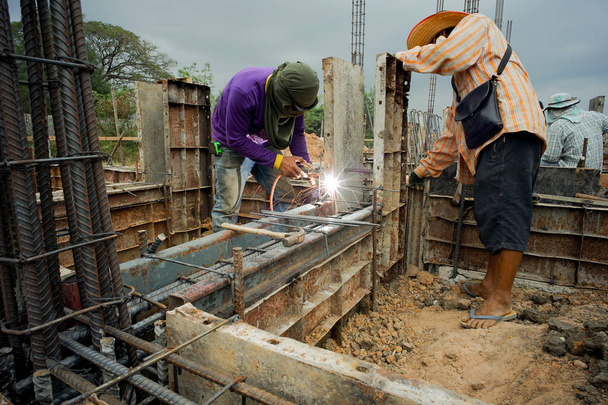 Workers welding the steel for supporting the mold of concrete structure at the construction site - Photo, image