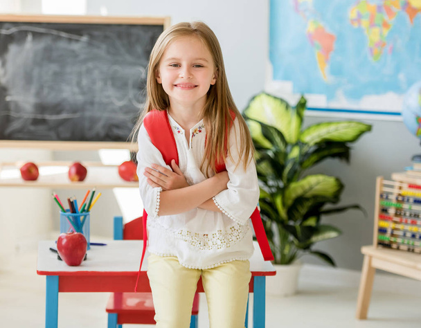 Little smiling blond girl standing in the school class - Foto, Bild