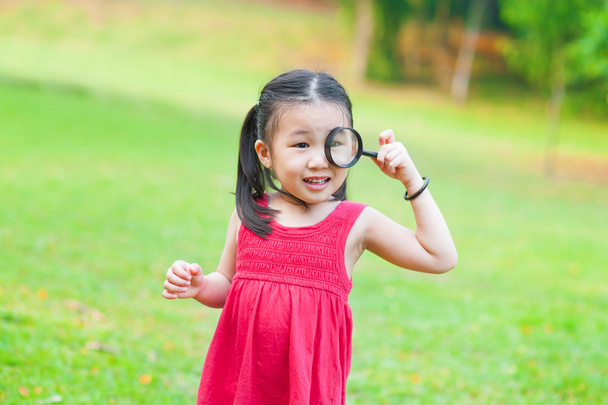 Little Asian girl with magnifier glass - Fotó, kép