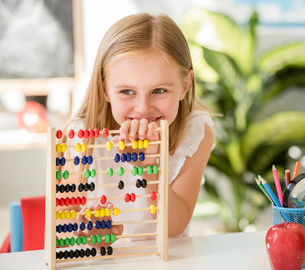 Little counting on the colourful abacus in the school classroom - Фото, изображение