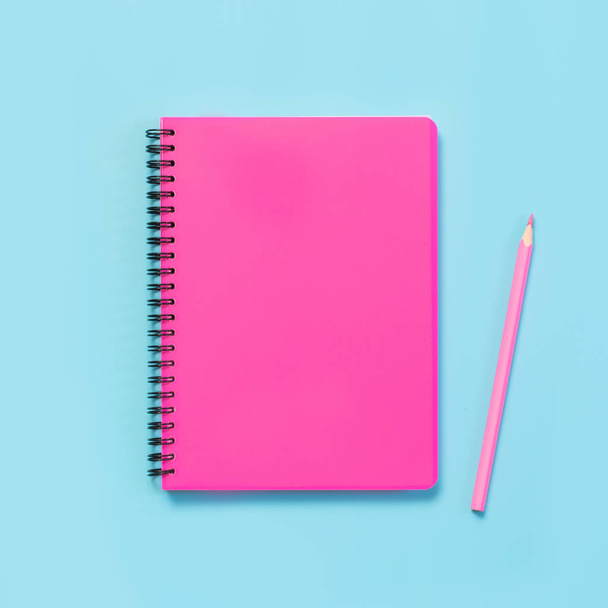 Material escolar femenino rosado, cuadernos y bolígrafos sobre fondo azul punzante. Vista superior, cama plana. Copiar espacio
. - Foto, imagen