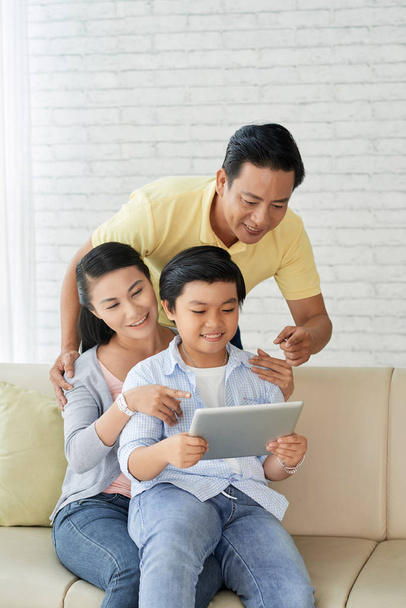 Loving family in cozy living room browsing digital tablet  - Photo, Image
