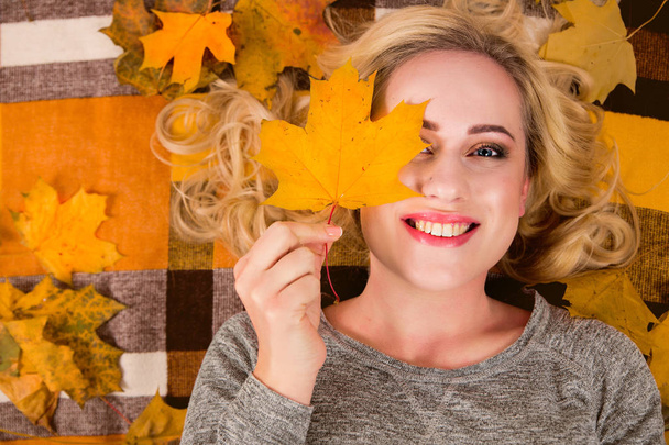 a menina encontra-se no coverlet nas folhas do outono
 - Foto, Imagem