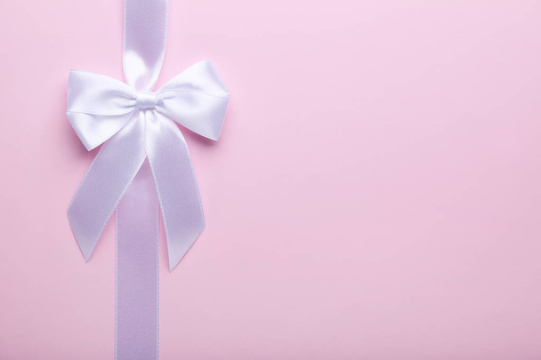 White bow with ribbon on pink background - Фото, изображение