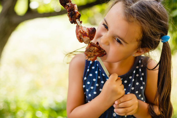 Kislány szórakozással eszi shish kebab - Fotó, kép