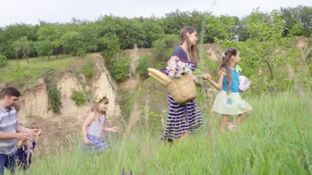 Young happy family with three children going for picnic in green hills. 4K - Footage, Video