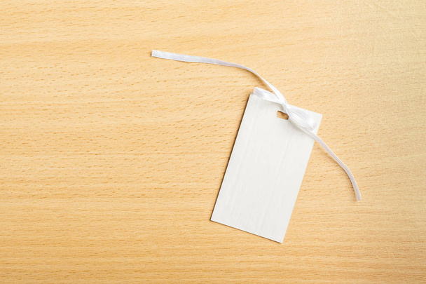 Blank tag with white ribbon on wooden background - 写真・画像