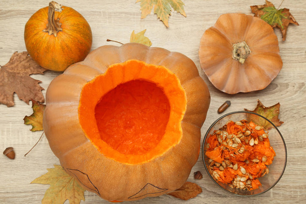 Orange pumpkin with dry leaves on wooden surface - Zdjęcie, obraz
