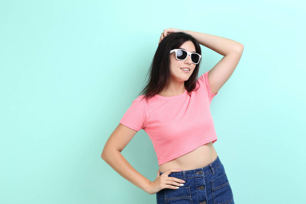 Young woman with sunglasses on mint background - Zdjęcie, obraz