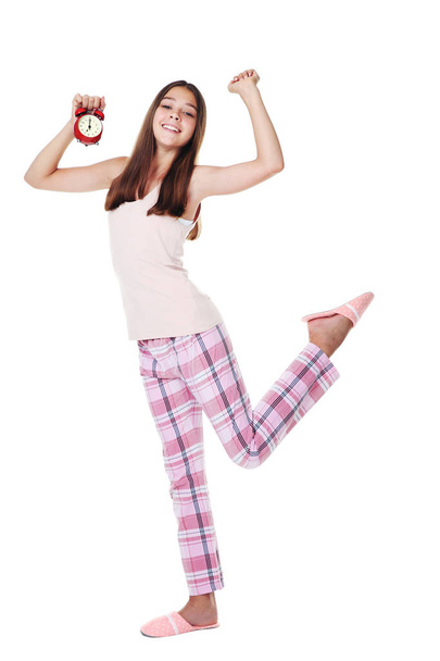 Young girl in pajamas with red alarm clock on white background - Foto, imagen