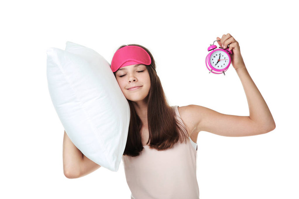 Young girl holding pillow and alarm clock on white background - Foto, Bild