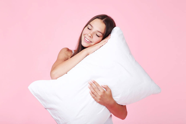 Young girl with white pillow on pink background - Foto, afbeelding