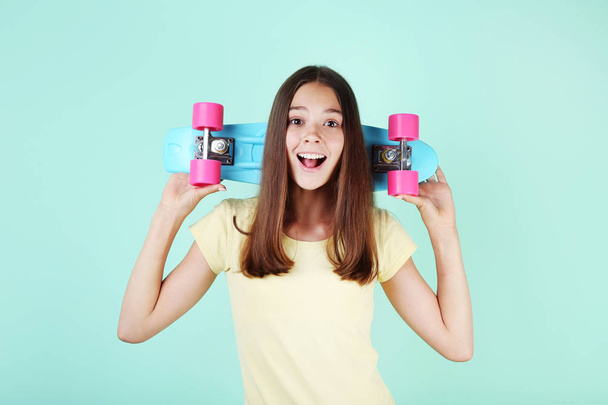 Young girl with skateboard on mint background - Foto, Imagen