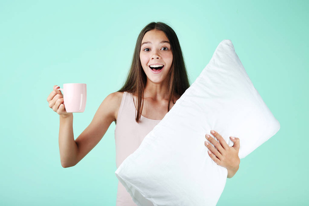 Young girl with white pillow and cup on mint background - Φωτογραφία, εικόνα