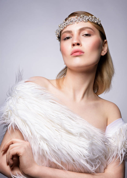 Close up beauty portrait of a pretty young blonde woman with perfect skin in faux fur on grey background - Photo, Image