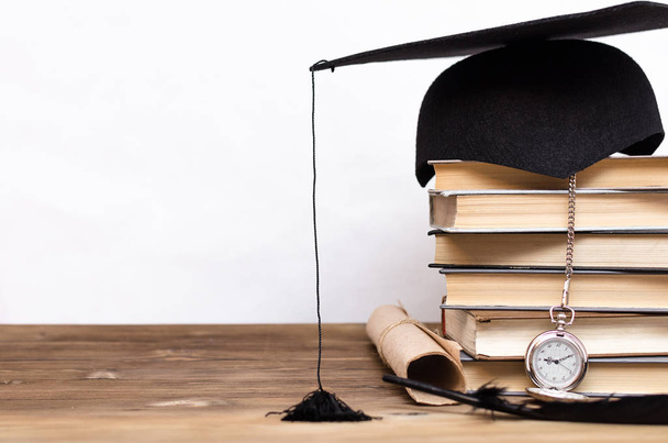 Stack of books, graduate cap, diploma and pocket watch on the school desk isolated on white background. - Foto, immagini