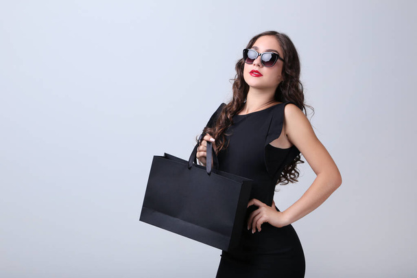 glückliche Frau mit Einkaufstasche auf grauem Hintergrund - Foto, Bild