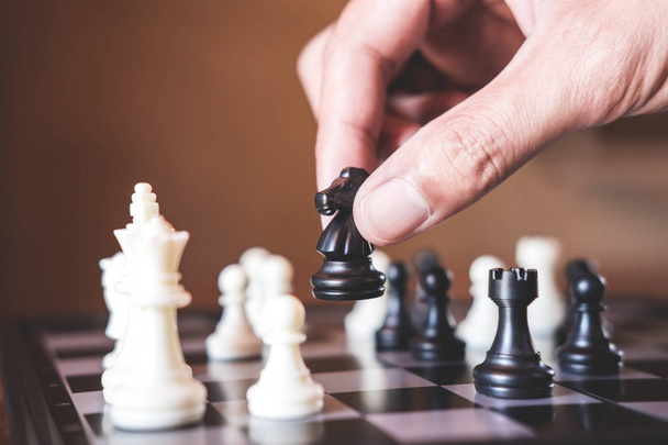 Hand of confident businessman use horse chess piece black playing chess game to development analysis new strategy plan, business strategy for win and success. - Foto, Imagen