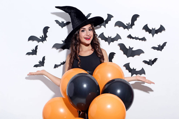 Young woman in halloween costume with balloons on white background - Foto, Imagem