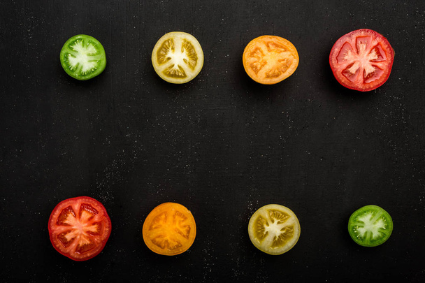 Tomates coloreados cortados por la mitad en la parte superior e inferior del marco. Verduras frescas, espacio para copiar
 - Foto, imagen