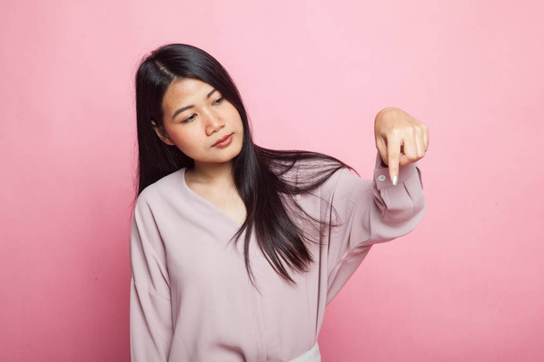Beautiful young Asian woman point down to blank space on pink background - Foto, afbeelding
