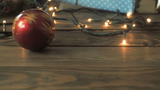 Getinte close-up video van de camera na rode kerst baublbe vallen op de vloer onder kerstboom - Video