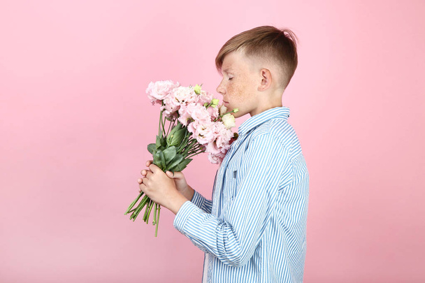 Beautiful young boy with eustoma flowers on pink background - Φωτογραφία, εικόνα