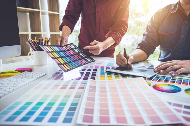 Δύο συνάδελφοι δημιουργικοί γραφίστες που εργάζονται στην επιλογή χρωμάτων και σχέδιο σε tablet γραφικών στο χώρο εργασίας. - Φωτογραφία, εικόνα