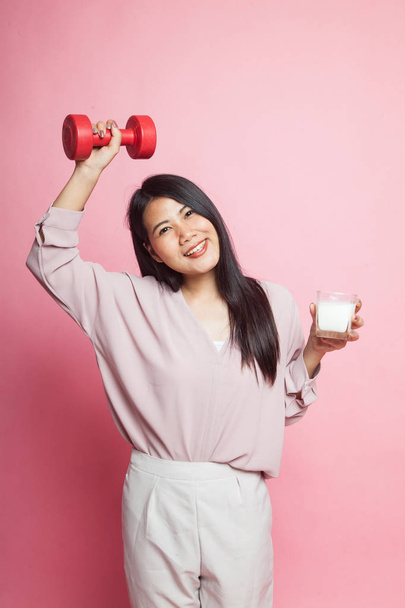 Healthy Asian woman drinking a glass of milk and dumbbell on pink background - Zdjęcie, obraz