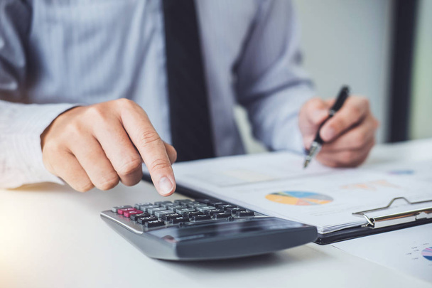 Business man or accountant working Financial investment on calculator with calculate Analyze business and market growth on financial document data graph and writing ,Accounting,Economic,commercial. - 写真・画像
