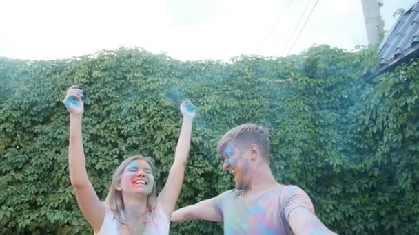 Młoda szczęśliwa para zabawy grając z proszek holi kolorowe - Materiał filmowy, wideo