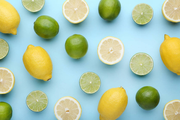 Ripe whole and halved lemons and limes on blue background - Foto, imagen