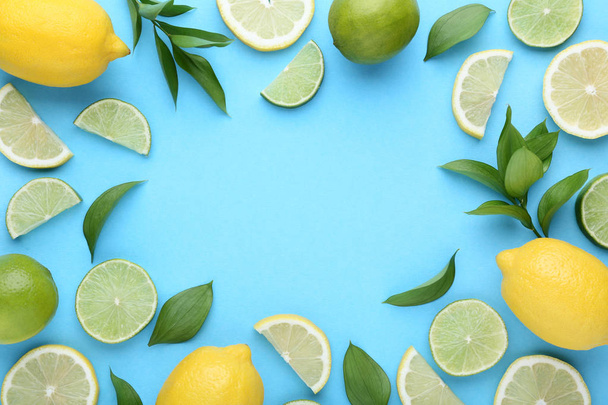 Ripe whole and sliced lemons and limes with green leaves on blue background - Foto, Imagem