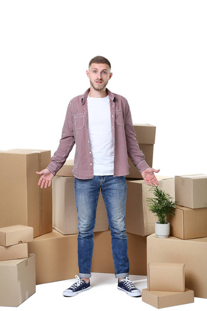 Young man with cardboard boxes on white background - Фото, изображение