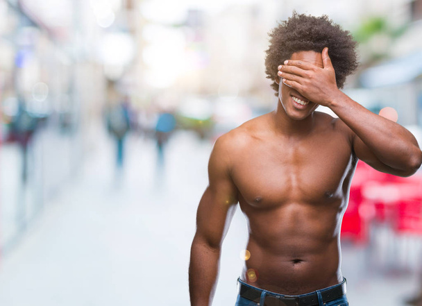 Afro americano uomo senza maglietta mostrando corpo nudo su sfondo isolato sorridente e ridente con gli occhi di copertura mano su faccia per sorpresa. Concetto cieco
. - Foto, immagini