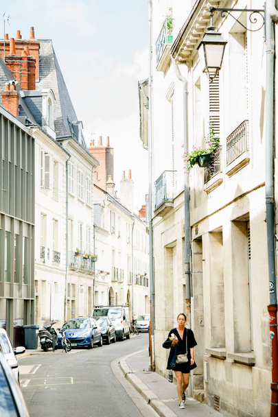 TOURS, FRANCE - AUGUST 14, 2018: woman walking on street with traditional french buildings and lovely summer atmosphere - Photo, Image